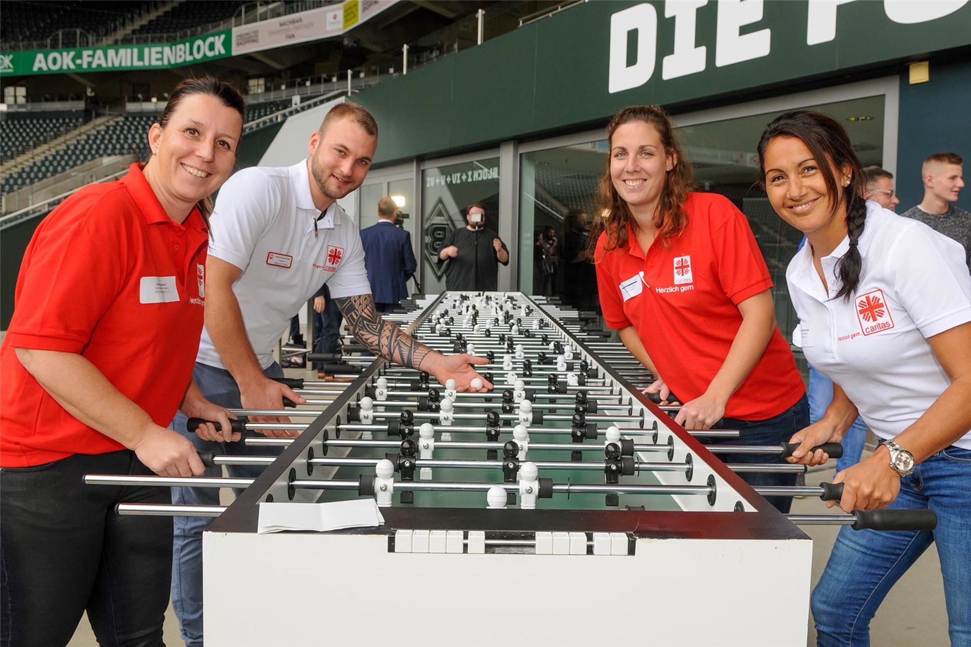 Vier Caritas-Mitarbeitende spielen am Kickertisch